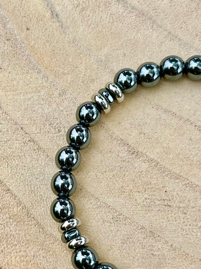 Bracelet CAMILLE, avec pierres d'Hématite, exposé sur un rondin de bois.