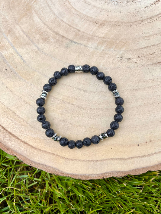 Bracelet CAMILLE, avec pierres de Lave, exposé sur un rondin de bois.