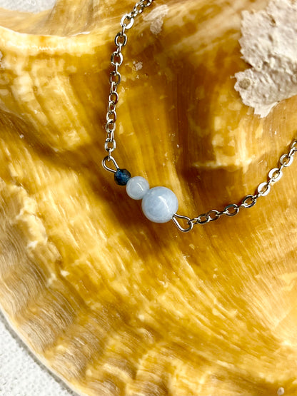 Bracelet EMMA, avec pierres d'Angélite et de Saphir, exposé sur un coquillage.