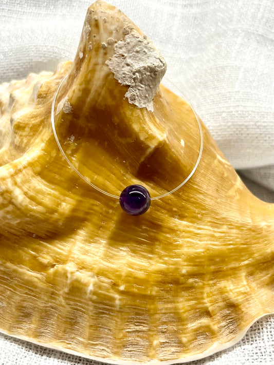 Collier EMY en pierre d'Améthyste, exposé sur un coquillage.