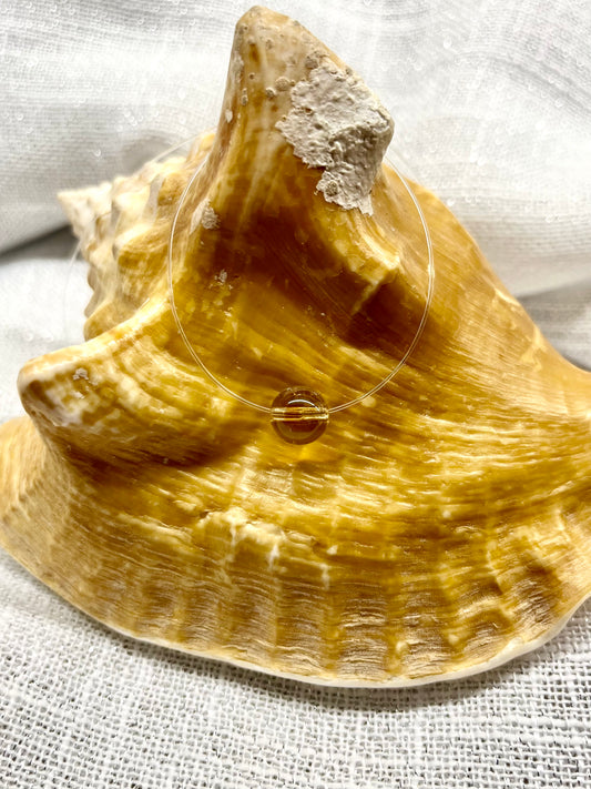 Collier EMY, avec pierre de Citrine, exposé sur un coquillage.
