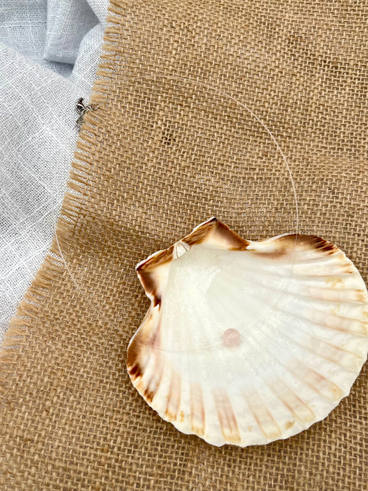 Collier EMY, avec pierre de Quartz Rose, exposé dans un coquillage.
