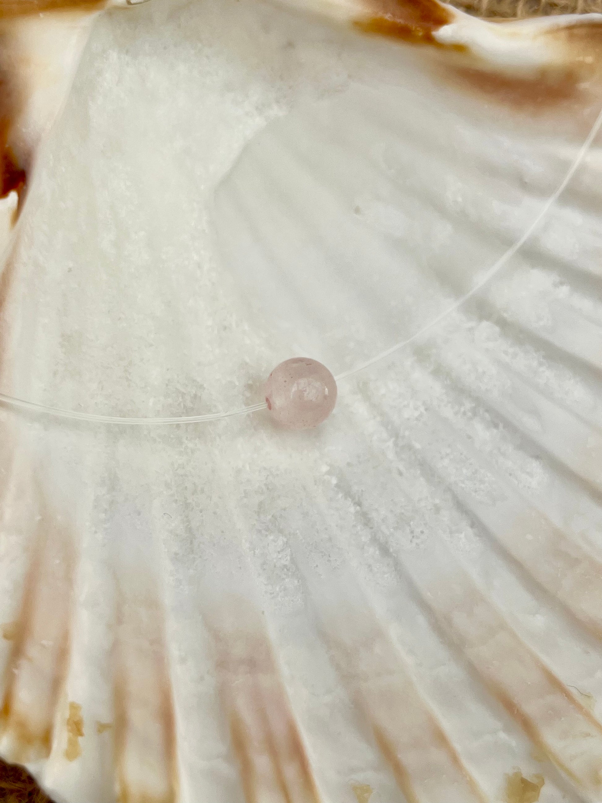 Collier EMY, avec pierre de Quartz Rose, exposé dans un coquillage.