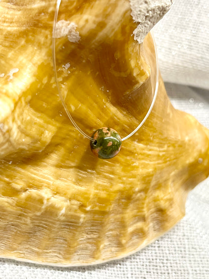 Collier EMY avec pierre d'Unakite, exposé sur un coquillage.