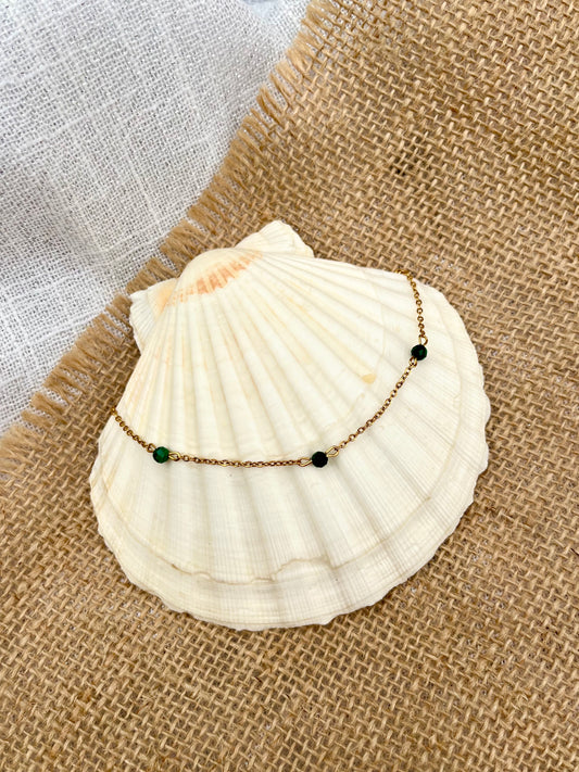 Collier EVA, avec pierre de Malachite, exposé sur un coquillage.