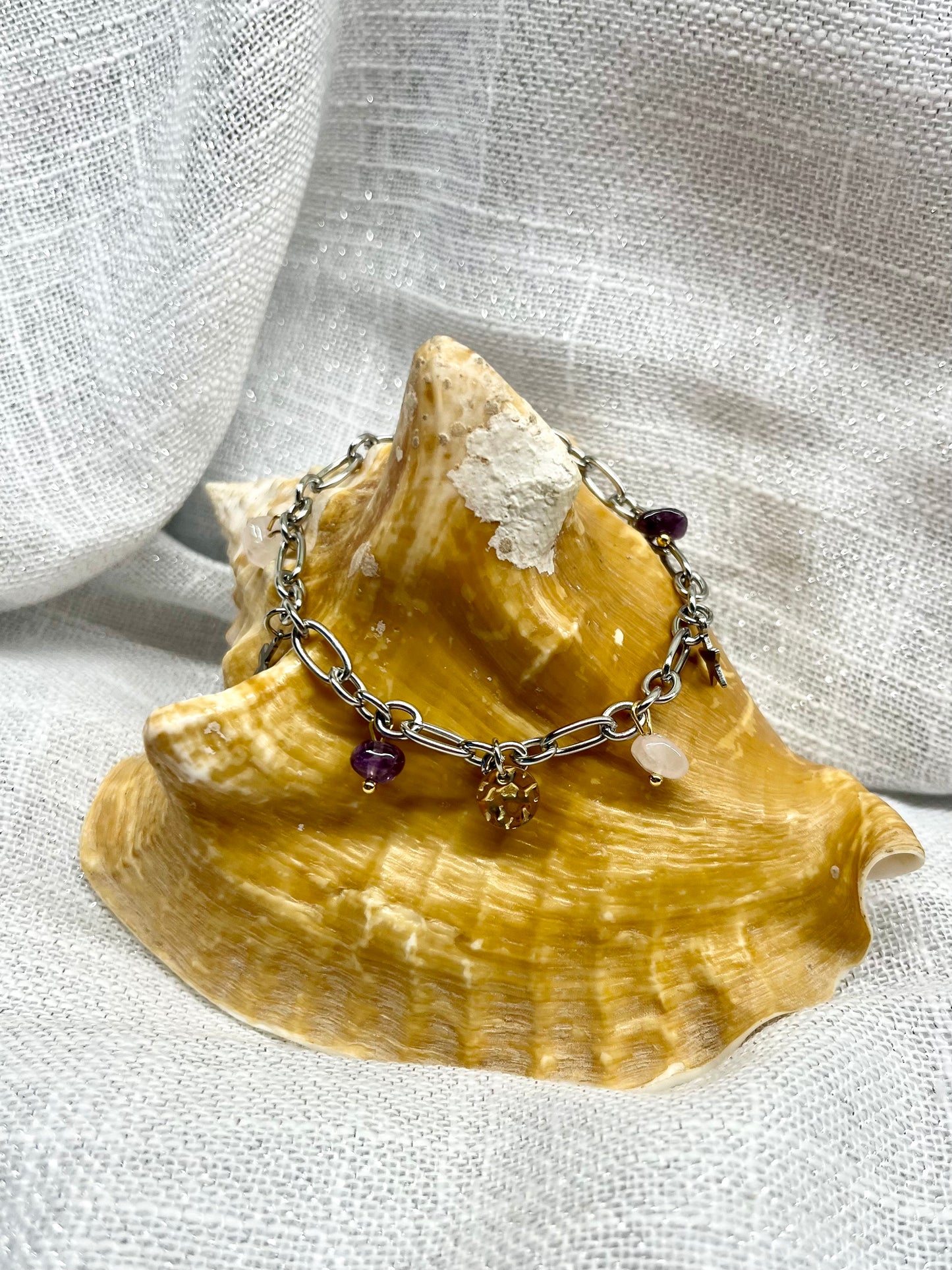 Bracelet JUDITH, avec pierres d'Améthyste et de Quartz Rose, exposé sur un coquillage.
