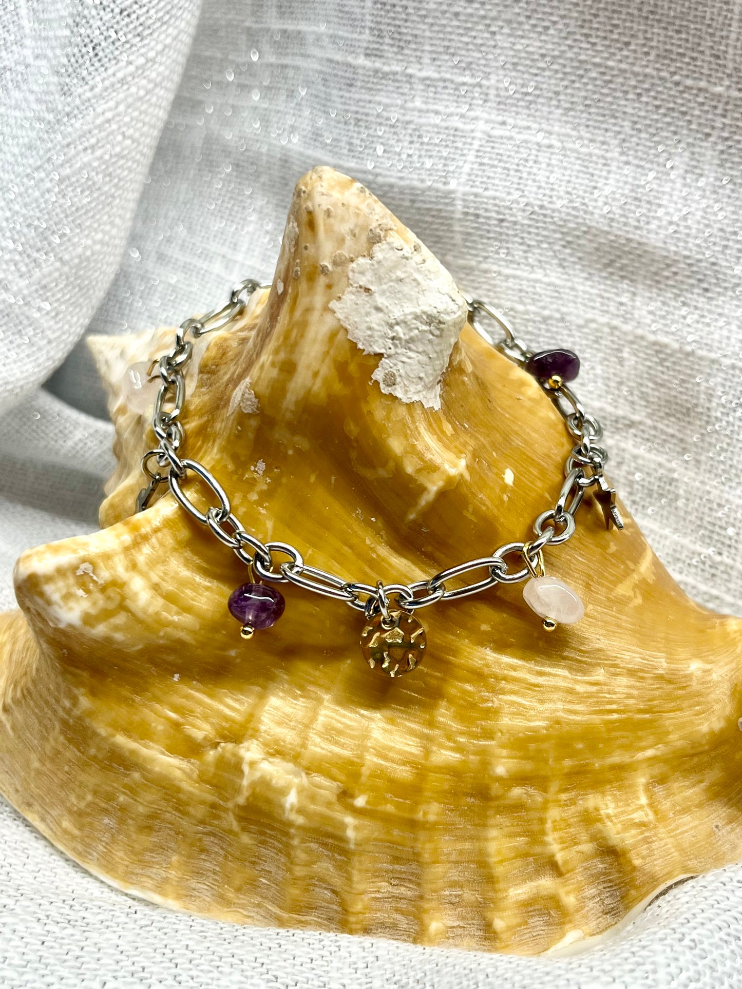 Bracelet JUDITH, avec pierres d'Améthyste et de Quartz Rose, exposé sur un coquillage.