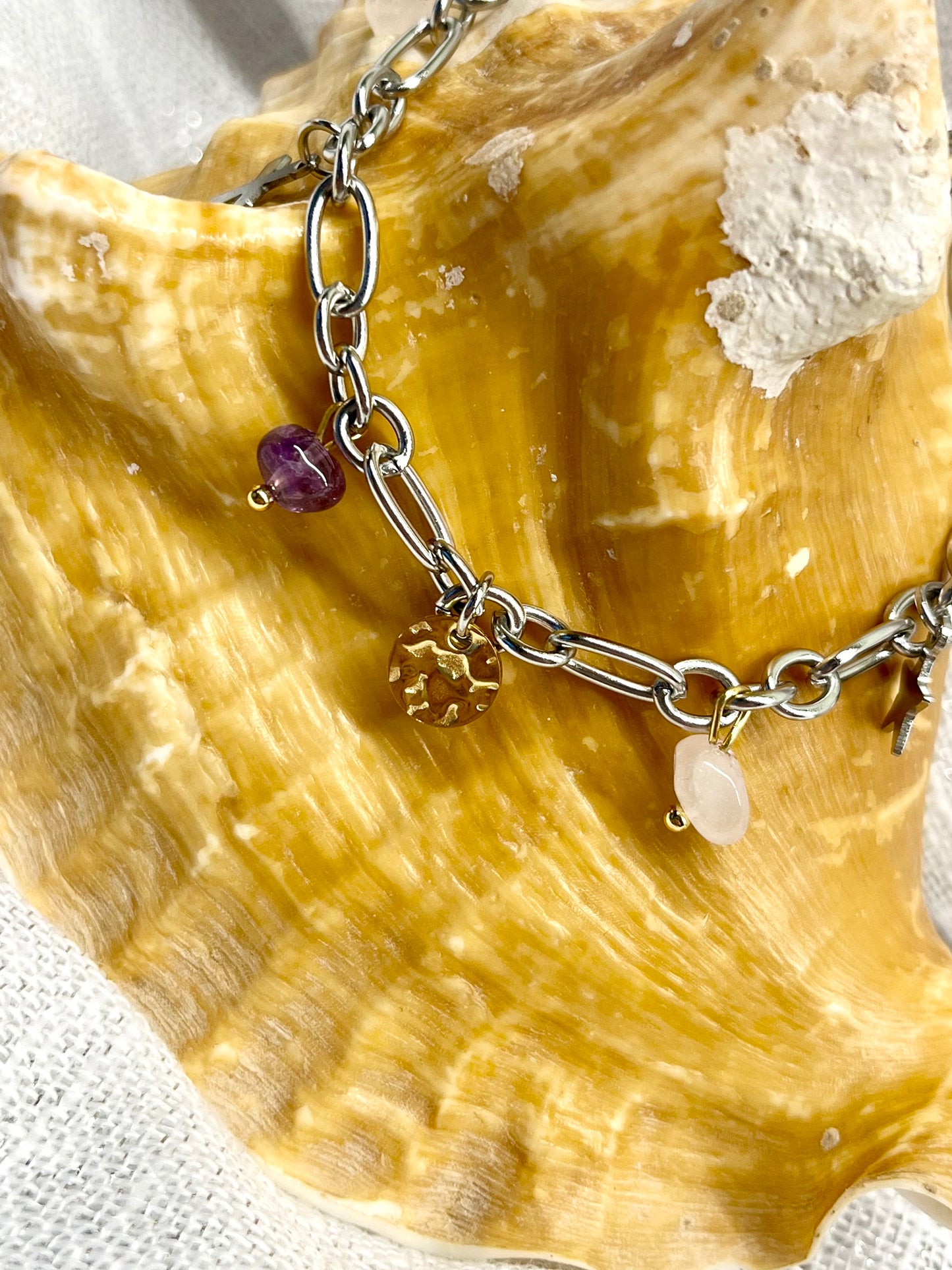 Bracelet JUDITH, avec pierres d'Améthyste et de Quartz Rose, exposé sur un coquillage.
