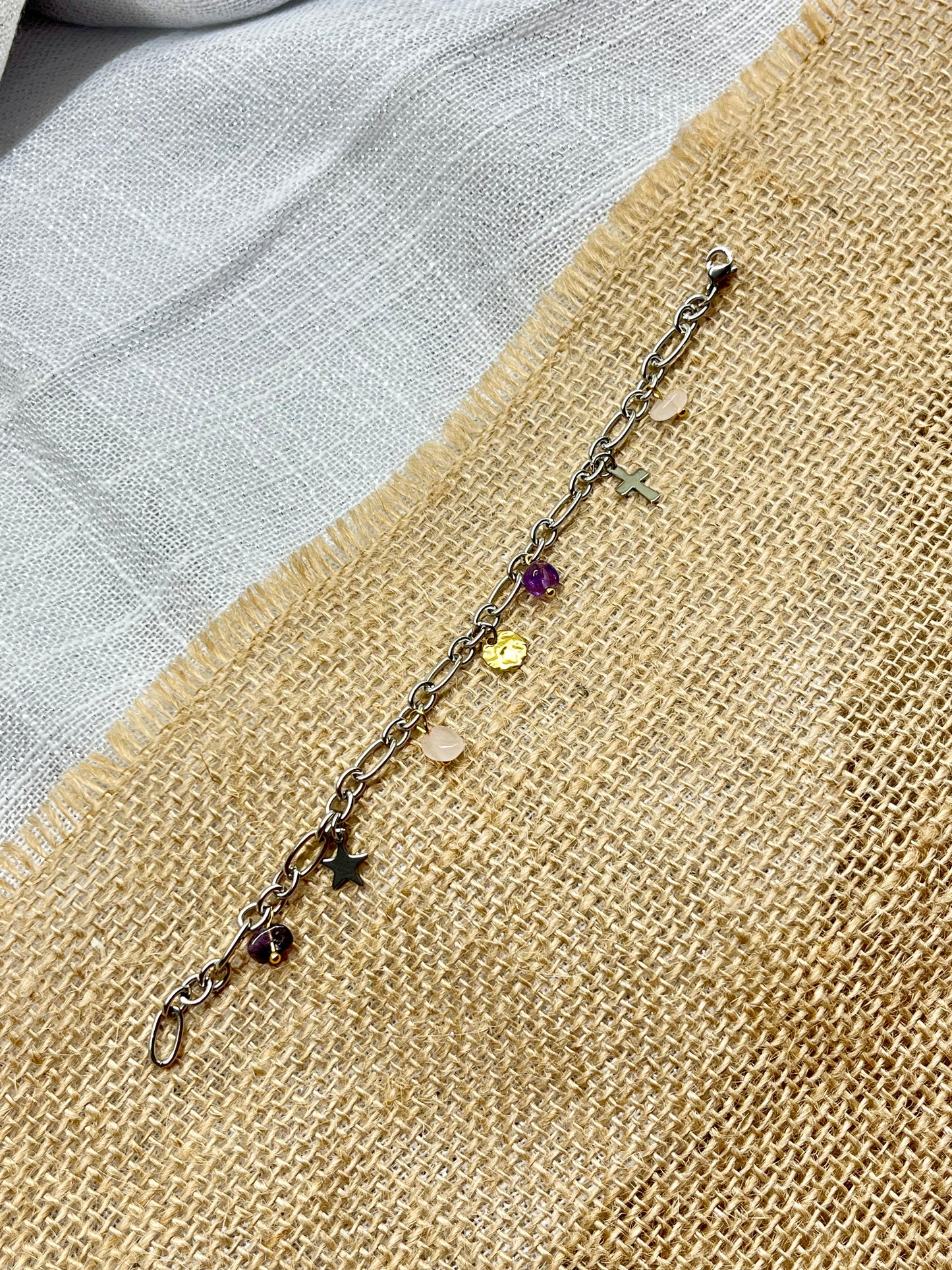 Bracelet JUDITH, avec pierres d'Améthyste et de Quartz Rose, exposé sur de la toile de jute.