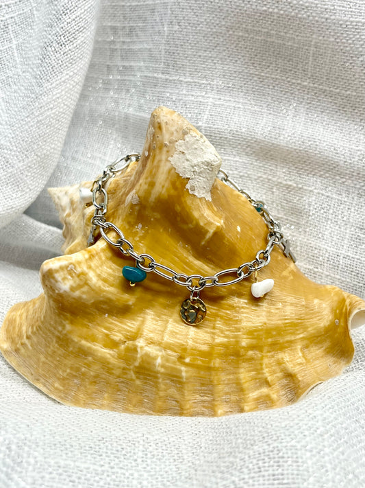Bracelet JUDITH, avec pierres de Howlite et d'Apatite, exposé sur un coquillage.