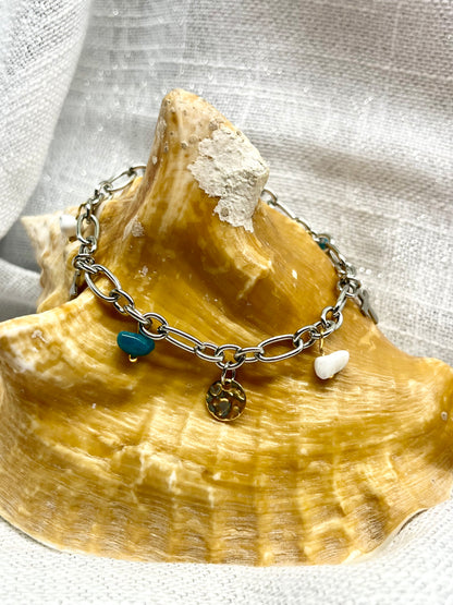 Bracelet JUDITH, avec pierres de Howlite et d'Apatite, exposé sur un coquillage.