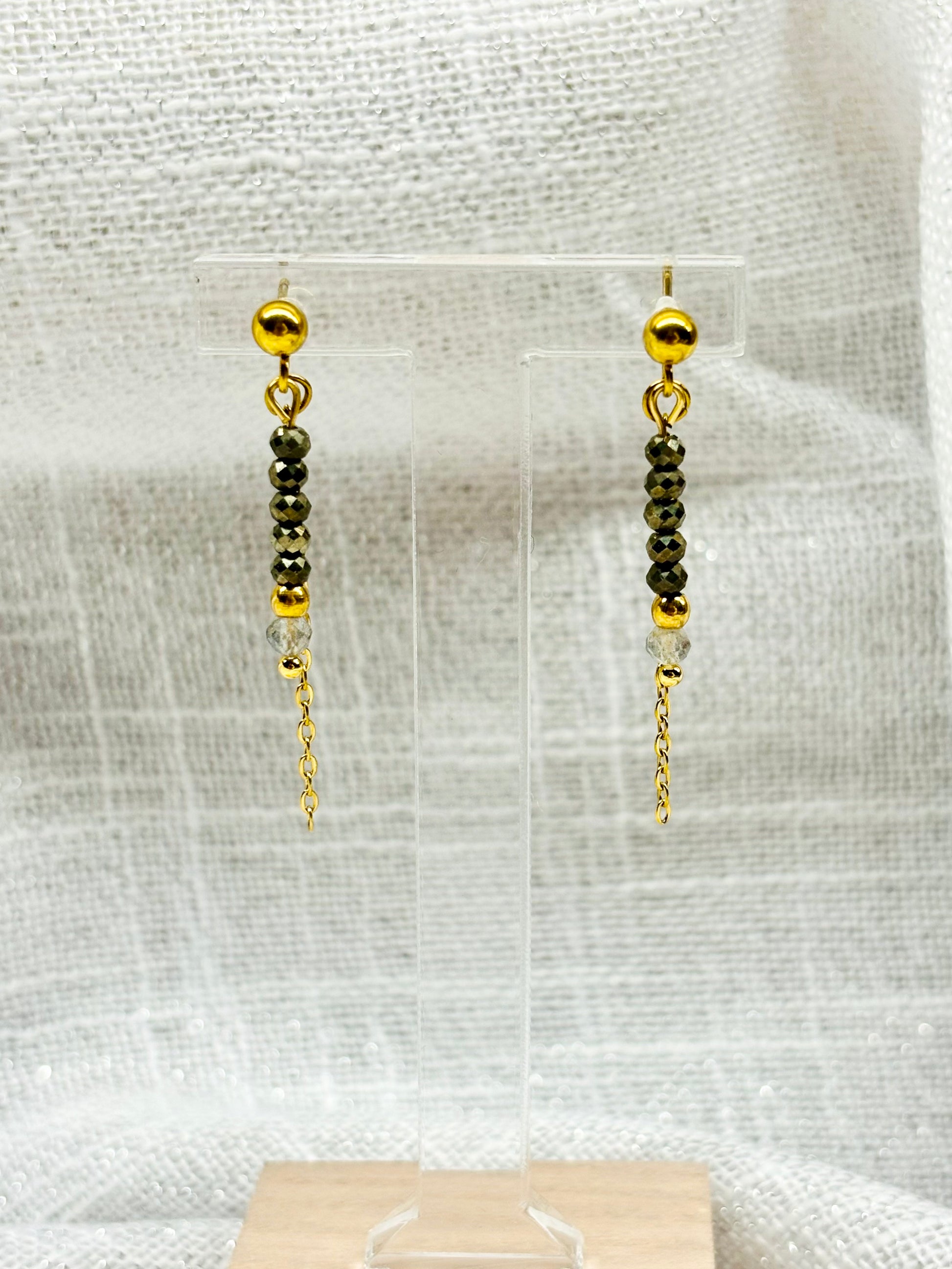 Boucles d'oreille JULIETTE, avec pierres de Pyrite et de Labradorite, exposées sur un fond en lin.