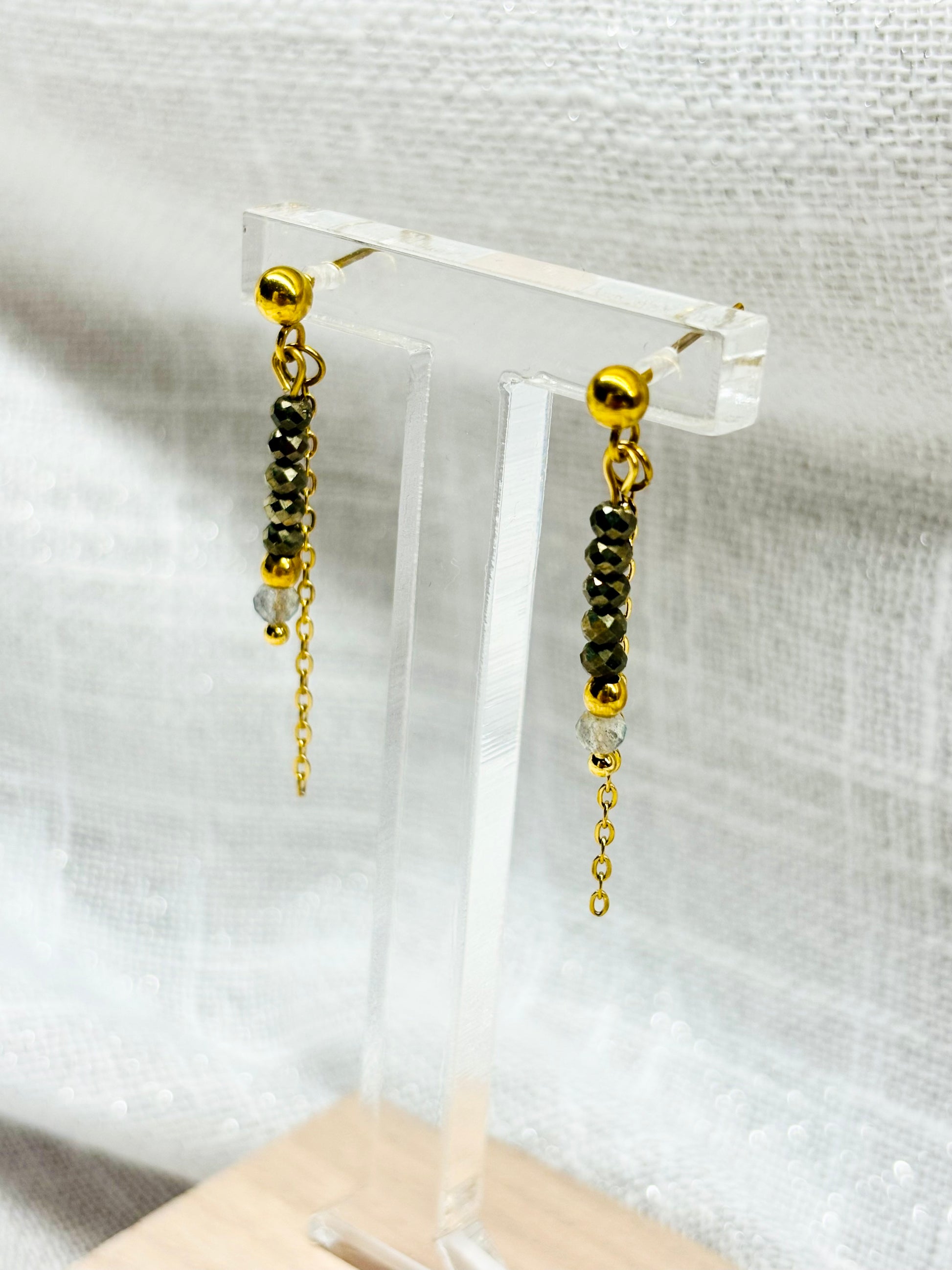 Boucles d'oreille JULIETTE, avec pierres de Pyrite et de Labradorite, exposées sur un fond en lin.