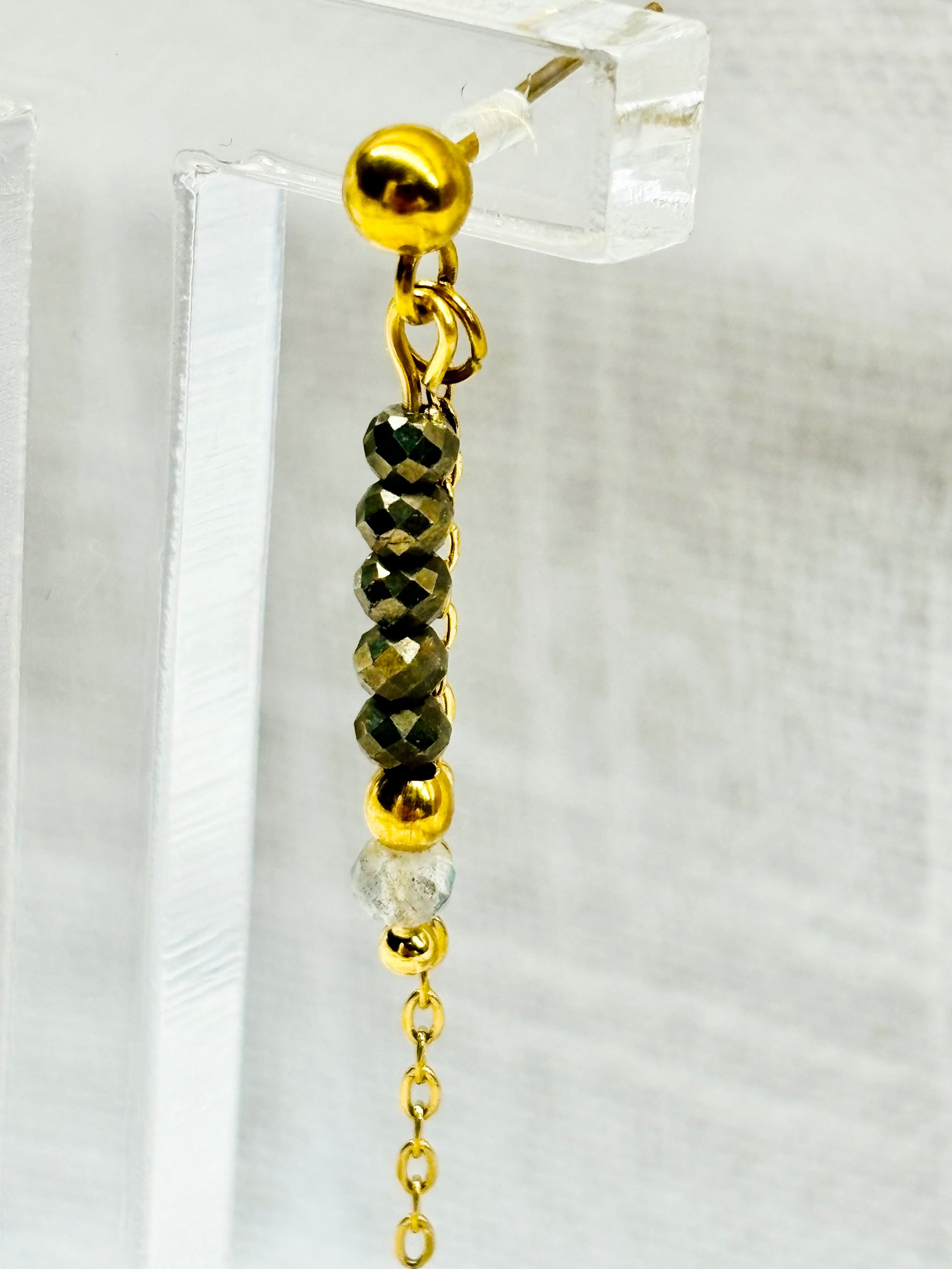 Boucles d'oreille JULIETTE, avec pierres de Pyrite et de Labradorite, exposées sur un fond en lin.