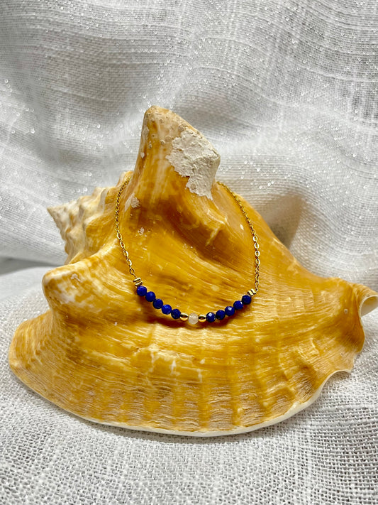 Collier JULIE, avec pierres de Lapis-Lazuli et de Labradorite, exposé sur un coquillage.