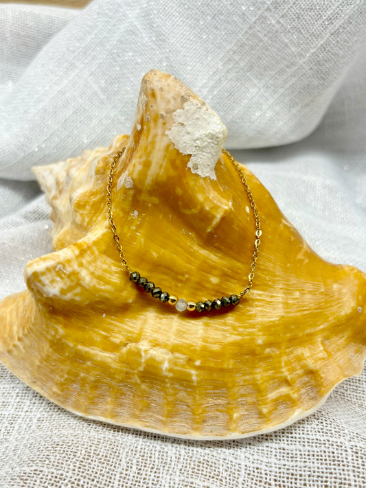 Collier JULIE, avec pierres de Pyrite et de Labradorite, exposé sur un coquillage.