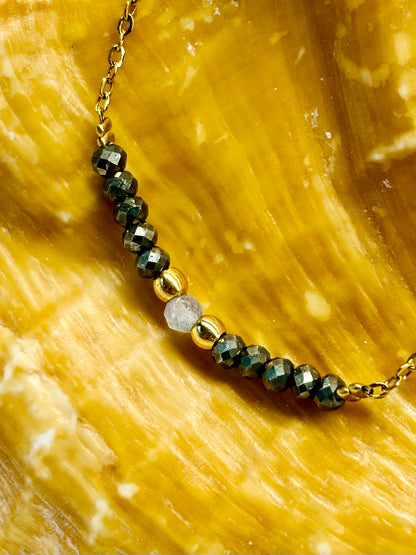 Collier JULIE, avec pierres de Pyrite et de Labradorite, exposé sur un coquillage.