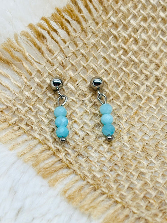 Boucles d'oreille LALY, avec pierres d'Amazonite, exposées sur de la toile de jute.