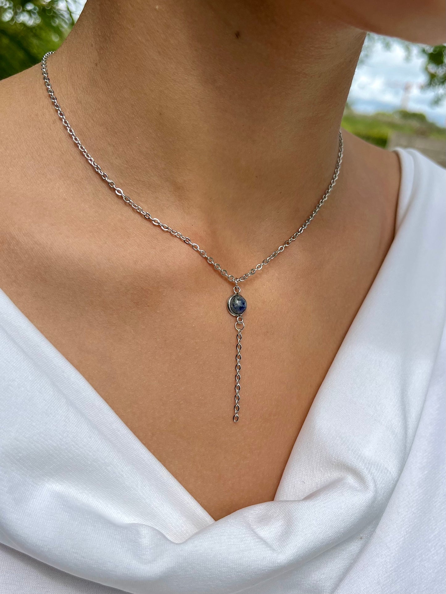 Collier LÉA, en acier inoxydable argent et pierre de Sodalite, porté sur un haut blanc.