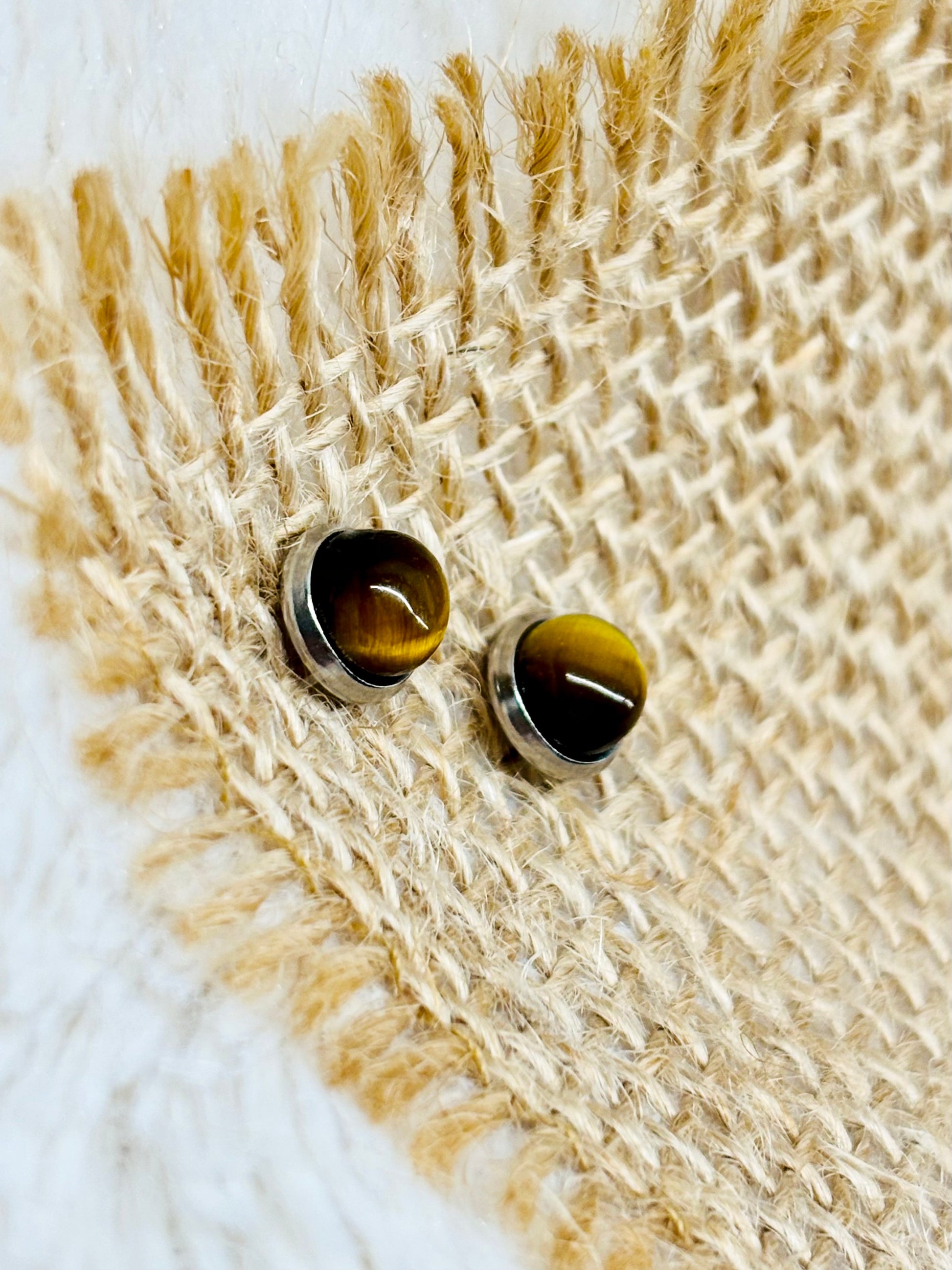 Boucles d'oreille LISE, avec pierre d'oeil de Tigre, exposées sur un fond en toile de jute.