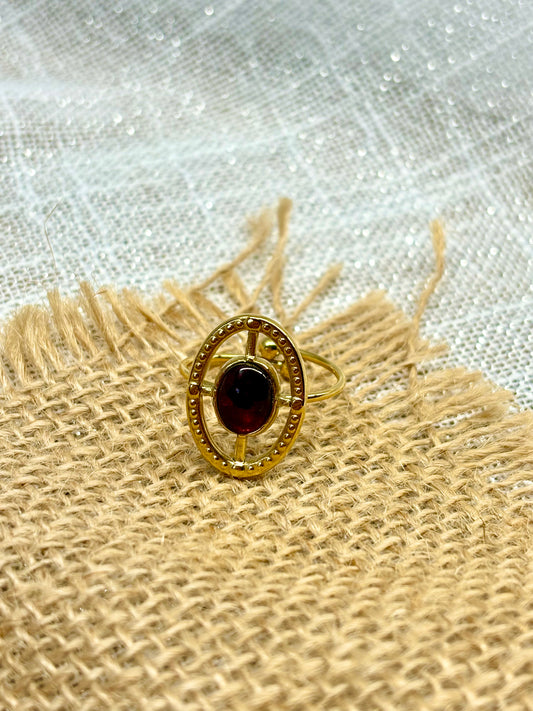 Bague LOUISE, avec pierre de Grenat, exposée sur de la toile de jute.