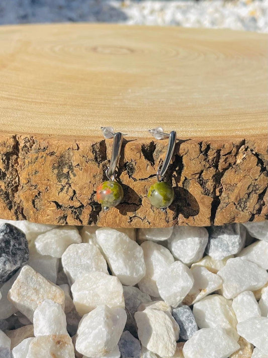 Boucles d'oreille MADELEINE, avec pierre d'Unakite, exposées sur un rondin de bois.