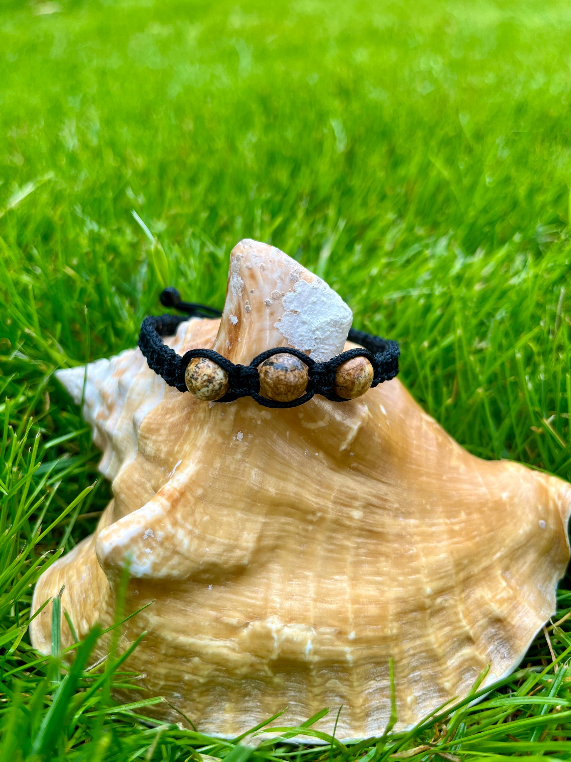 Bracelet MAËL, avec pierres de Jaspe Paysage, exposé sur un coquillage.