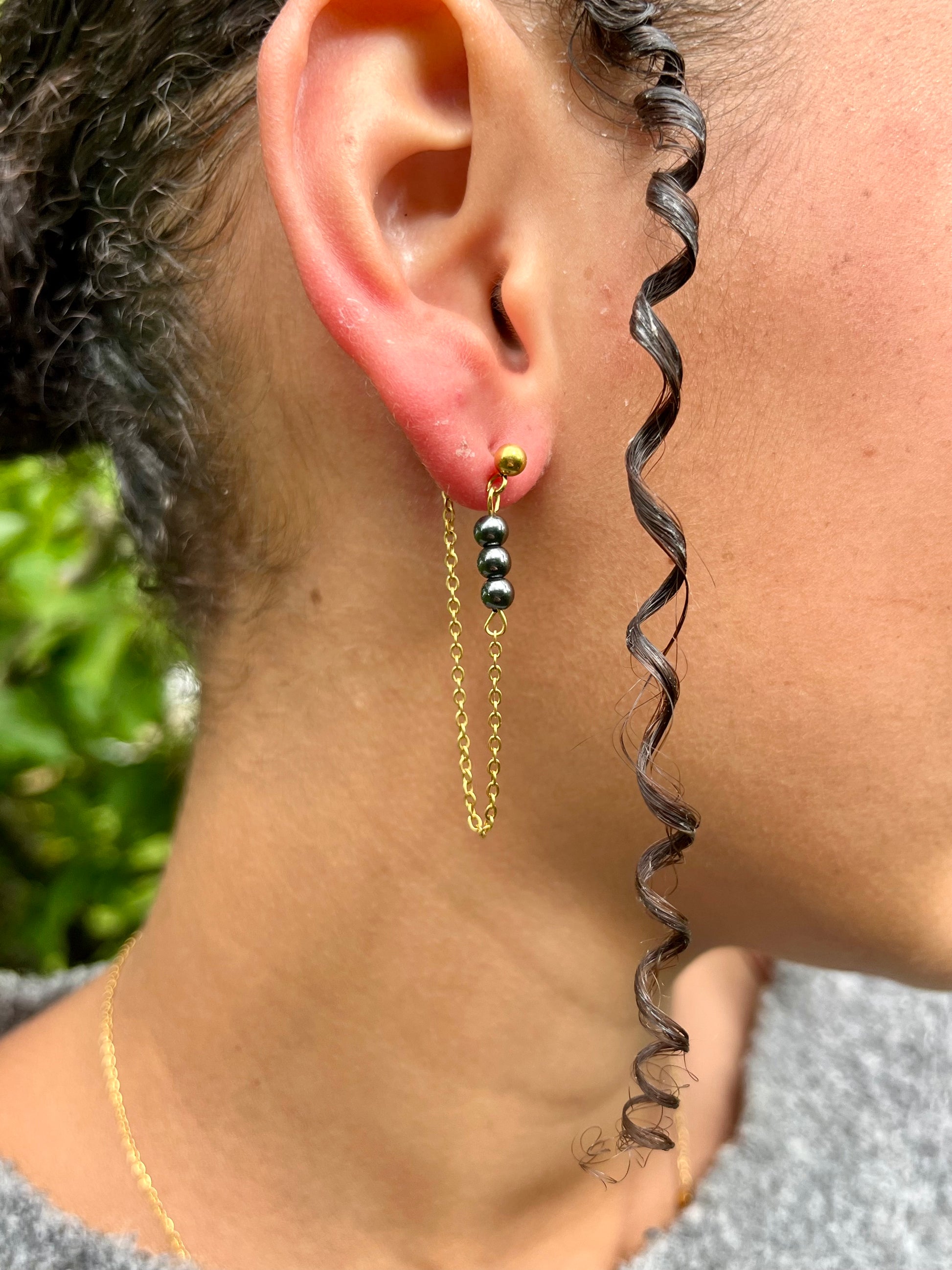 Boucles d'oreille MALIA, de couleur dorée avec pierres d'hématite, portées.