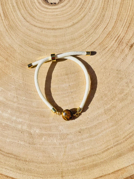 Bracelet MIA, avec cordon et pierre d'Oeil de Tigre, exposé sur un fond en bois.