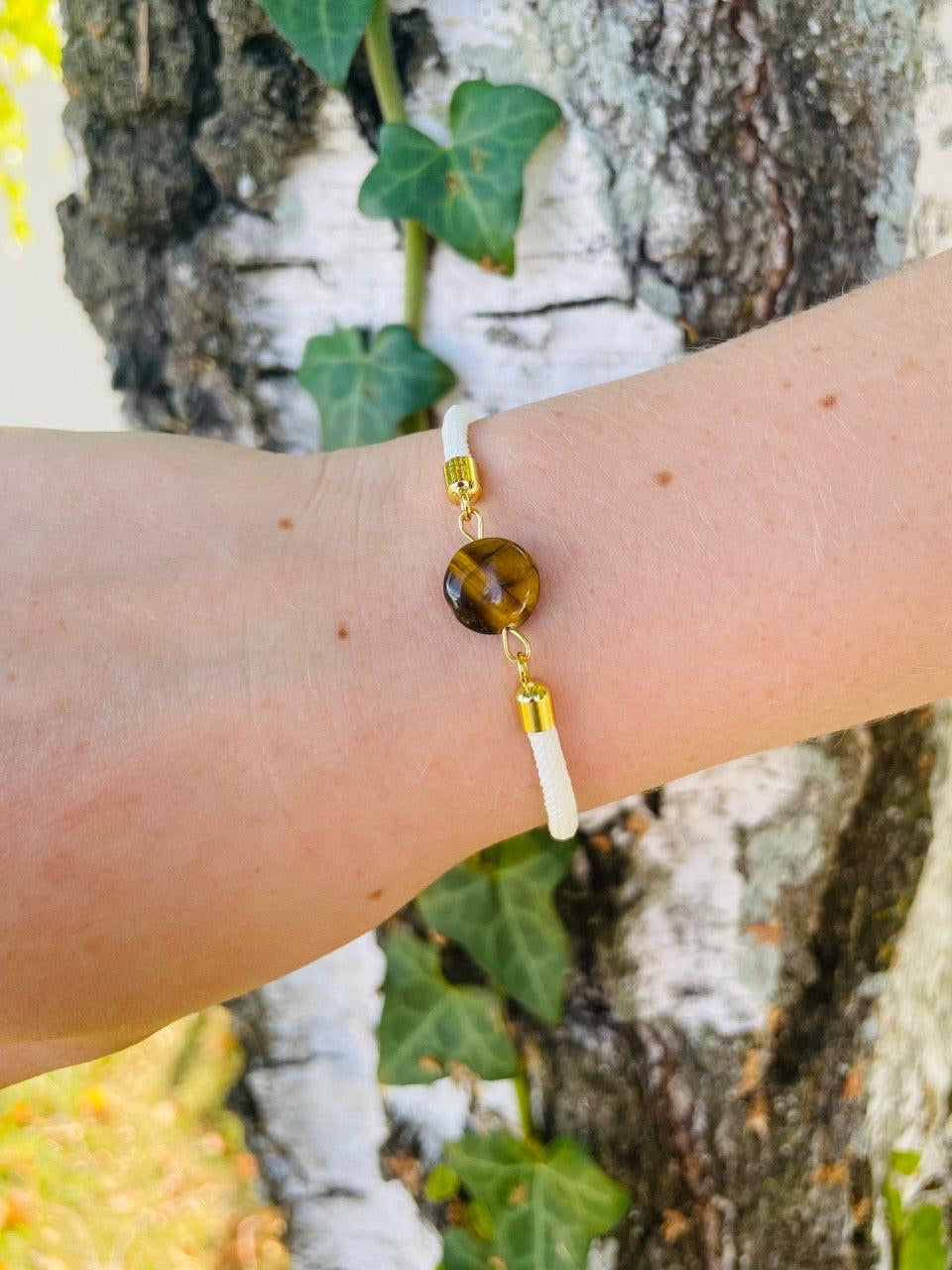 Bracelet MIA, avec cordon et pierre d'Oeil de Tigre, porté sur un poignet de femme.