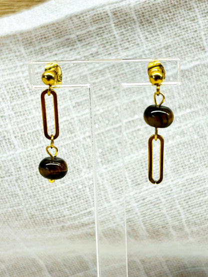 Boucles d'oreille NOËLA, avec pierre d'Oeil de Tigre, exposées sur un fond en lin.