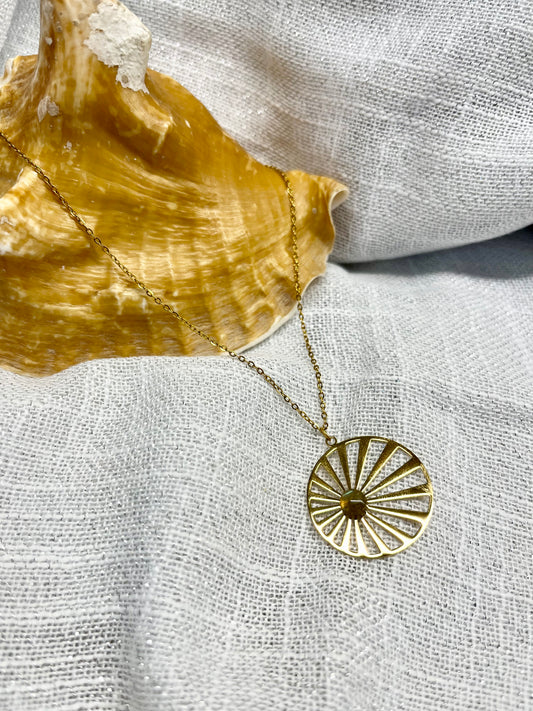 Collier SANA, de couleur dorée avec pierre de Labradorite, exposé sur un fond en lin.