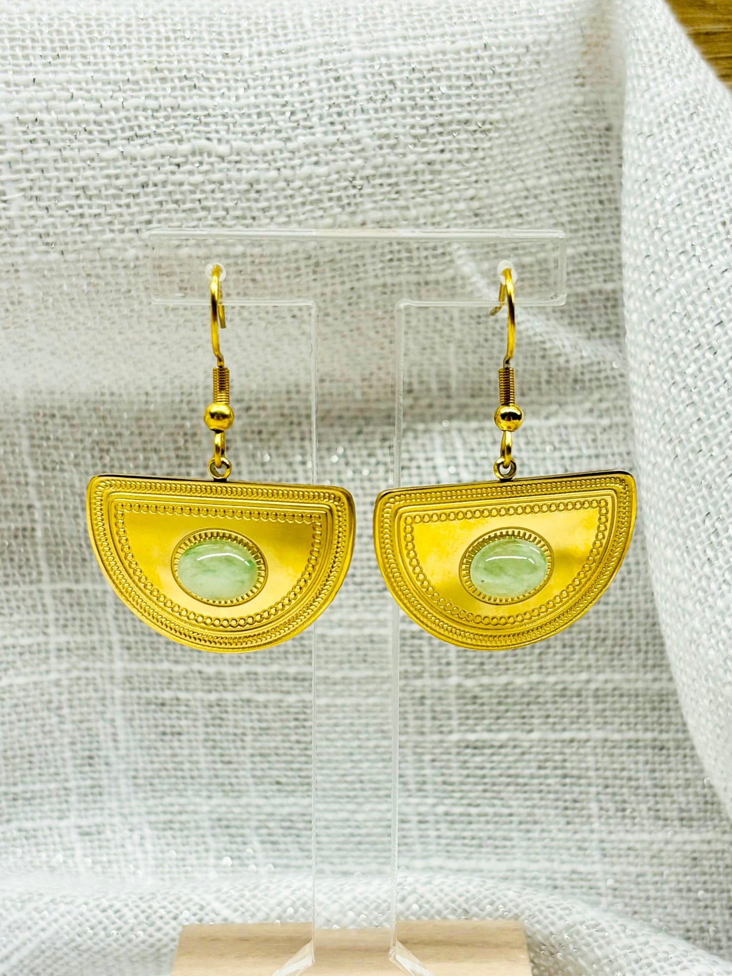 Boucles d'oreille SELENA, en acier inoxydable doré et pierre d'Aventurine, exposées sur un fond en lin.