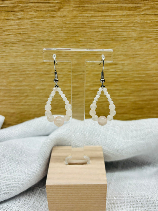 Boucles d'oreille SIMONA, avec pierres de Quartz Rose, exposées sur un fond en bois.