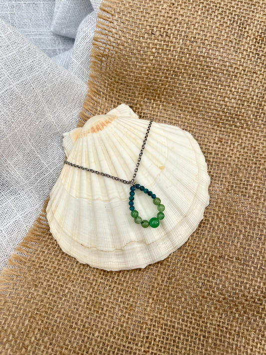 Collier SIMONA, avec pierres d'Aventurine et d'Apatite, exposé sur un coquillage.