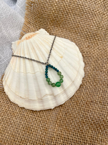 Collier SIMONA, avec pierres d'Aventurine et d'Apatite, exposé sur un coquillage.