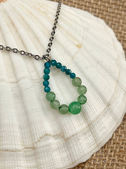 Collier SIMONA, avec pierres d'Aventurine et d'Apatite, exposé sur un coquillage.