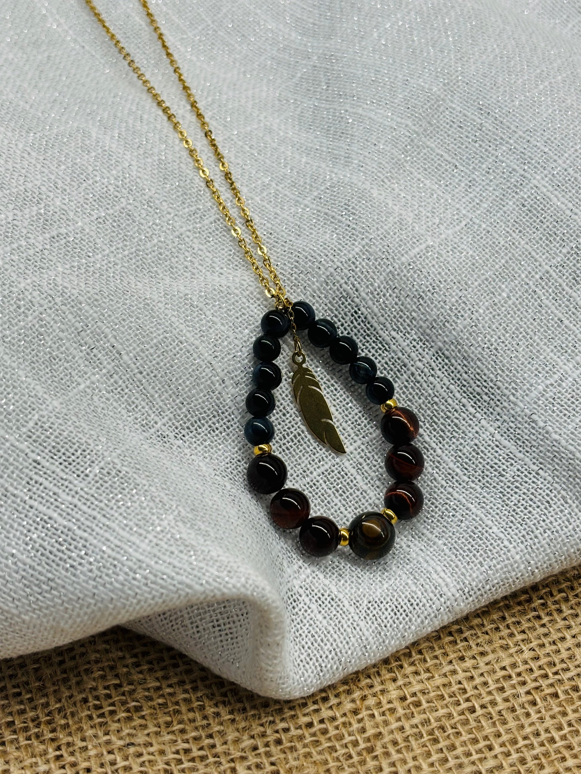 Collier SIMONE, avec pierre d'Oeil de Tigre, de Taureau et de Faucon, exposé sur un fond en lin.