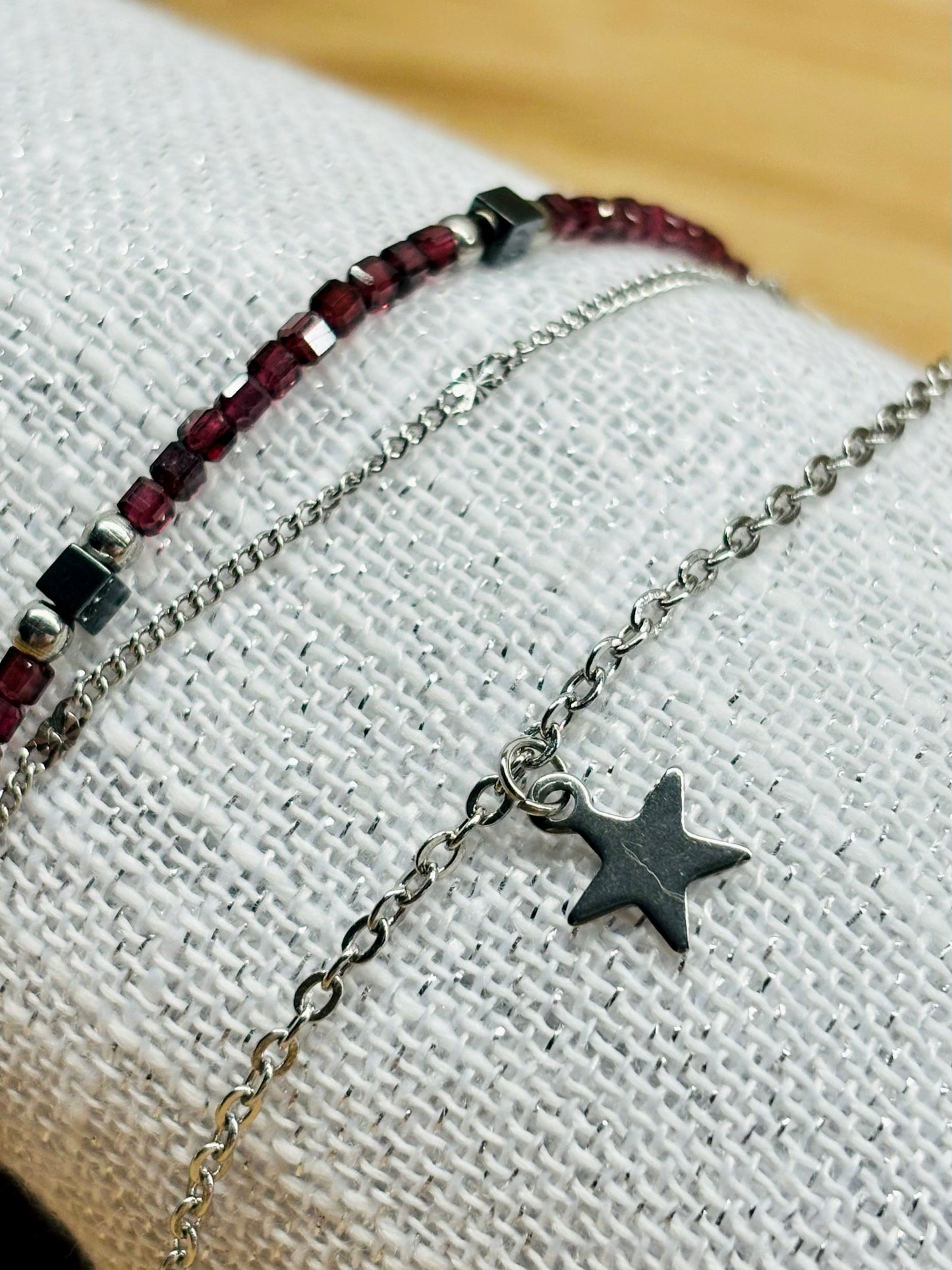 Bracelet STELLA, en acier inoxydable, avec pierre de Grenat et pierre d'Hématite, sur un coquillage.