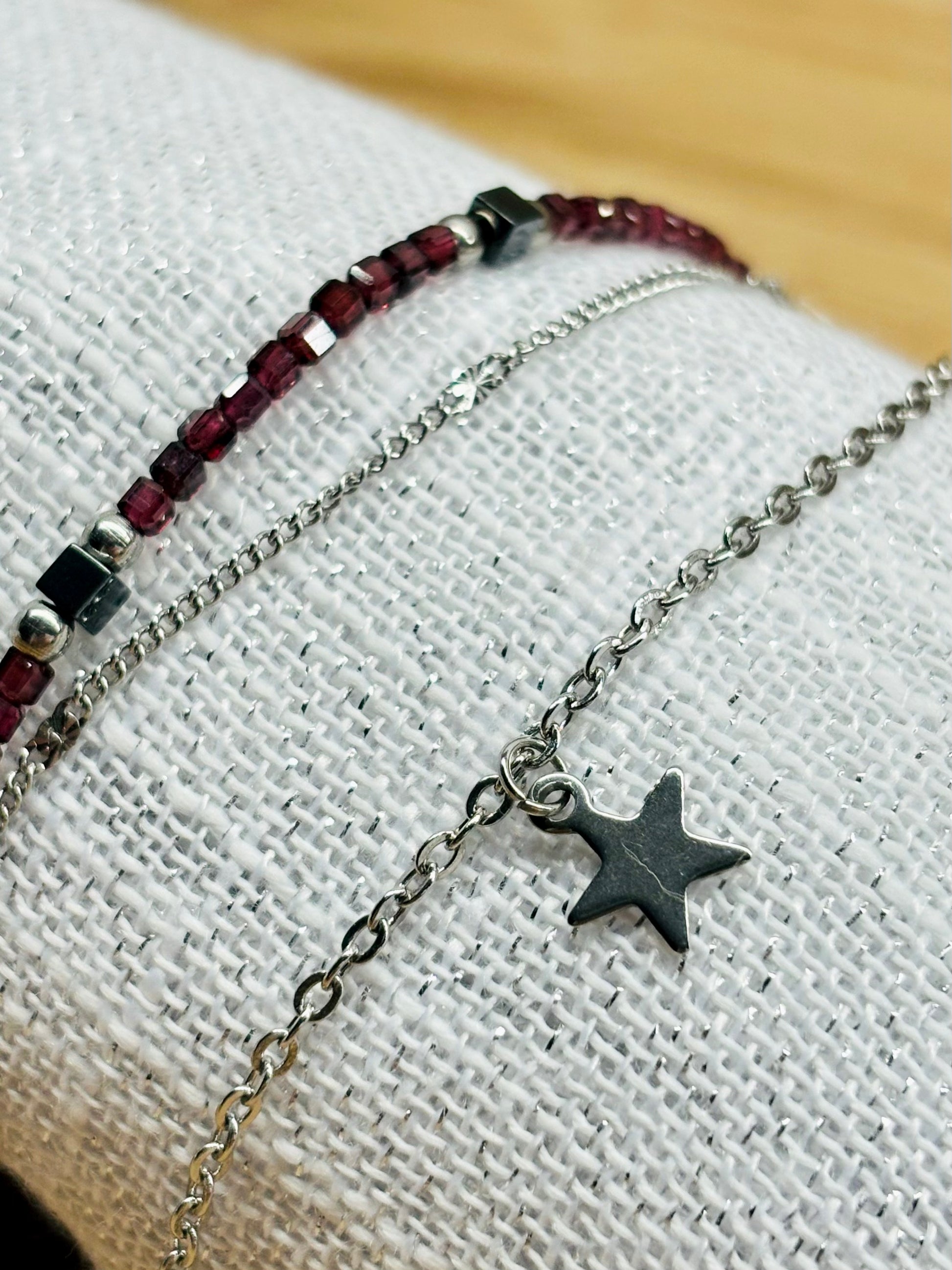Bracelet STELLA, en acier inoxydable, avec pierre de Grenat et pierre d'Hématite, sur un coquillage.