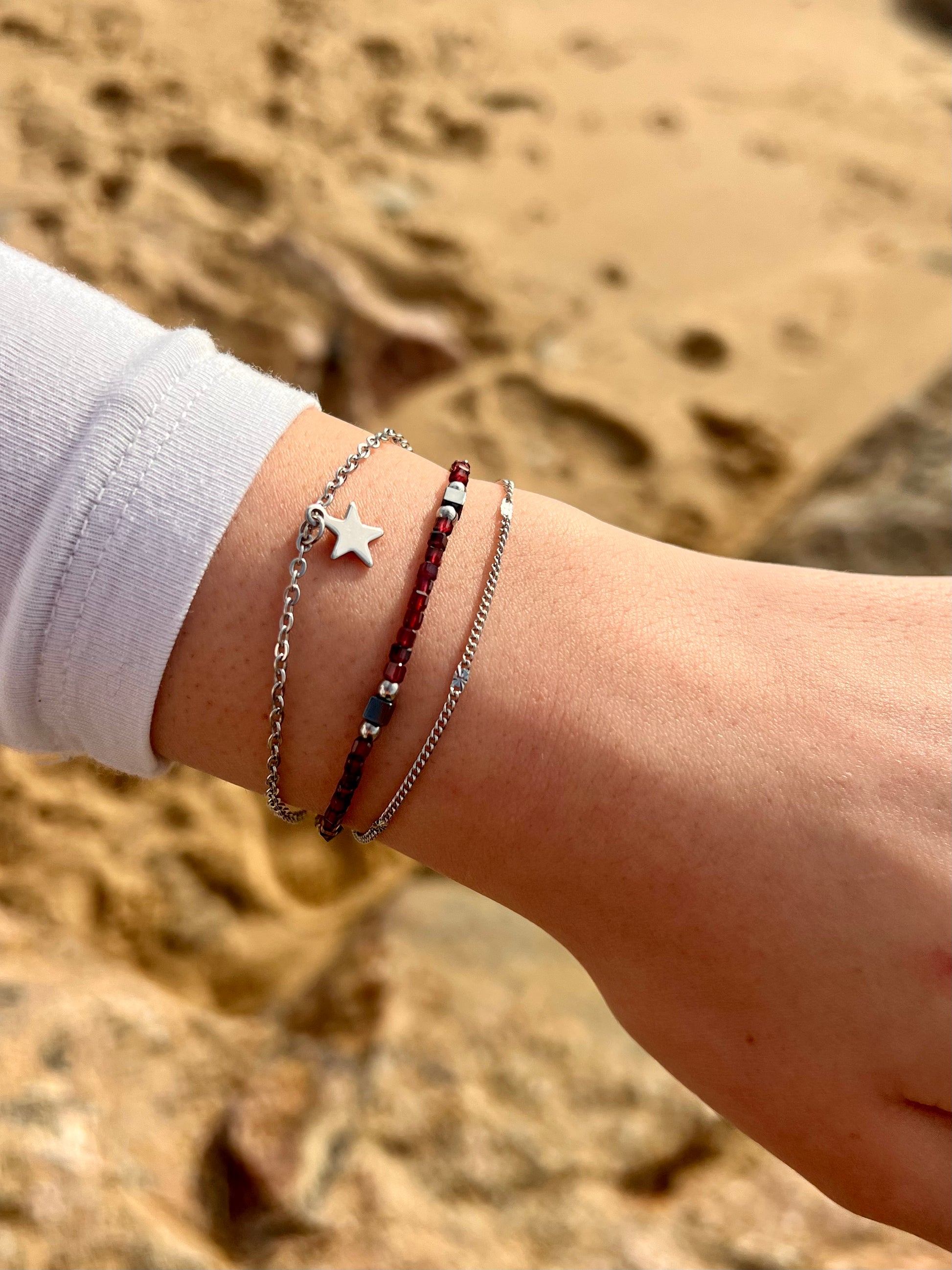 Bracelet STELLA, en acier inoxydable, avec pierre de Grenat et pierre d'Hématite, sur une main de femme.