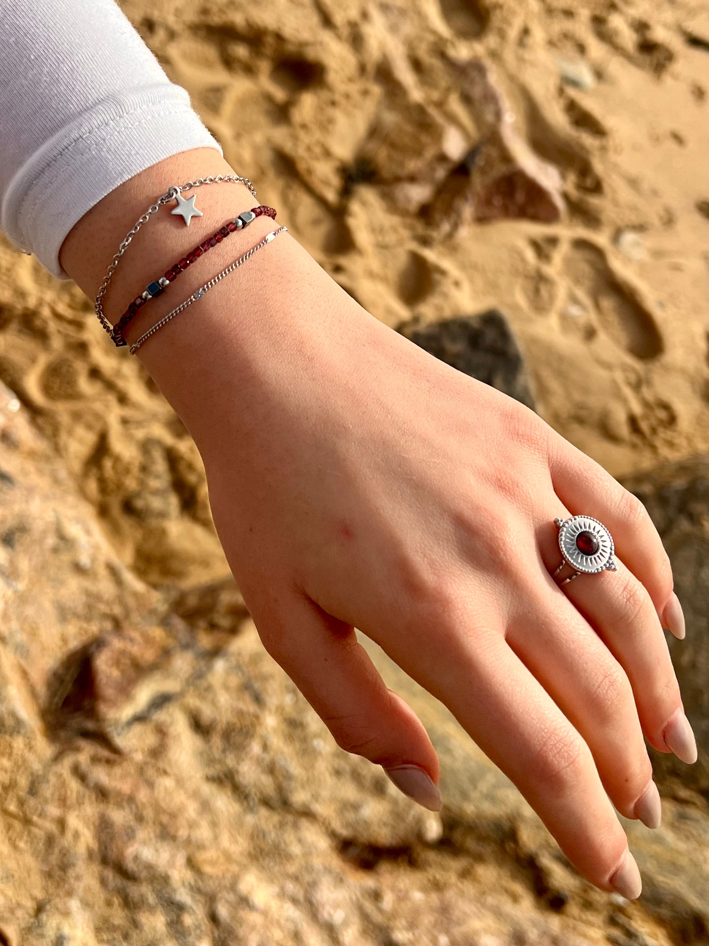 Bracelet STELLA, en acier inoxydable, avec pierre de Grenat et pierre d'Hématite, sur une main de femme.