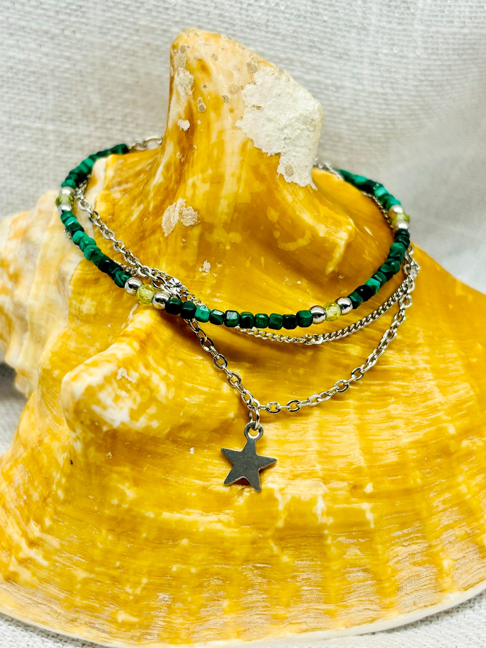 Bracelet STELLA, avec pierre de Malachite et Péridot, exposé sur un coquillage.