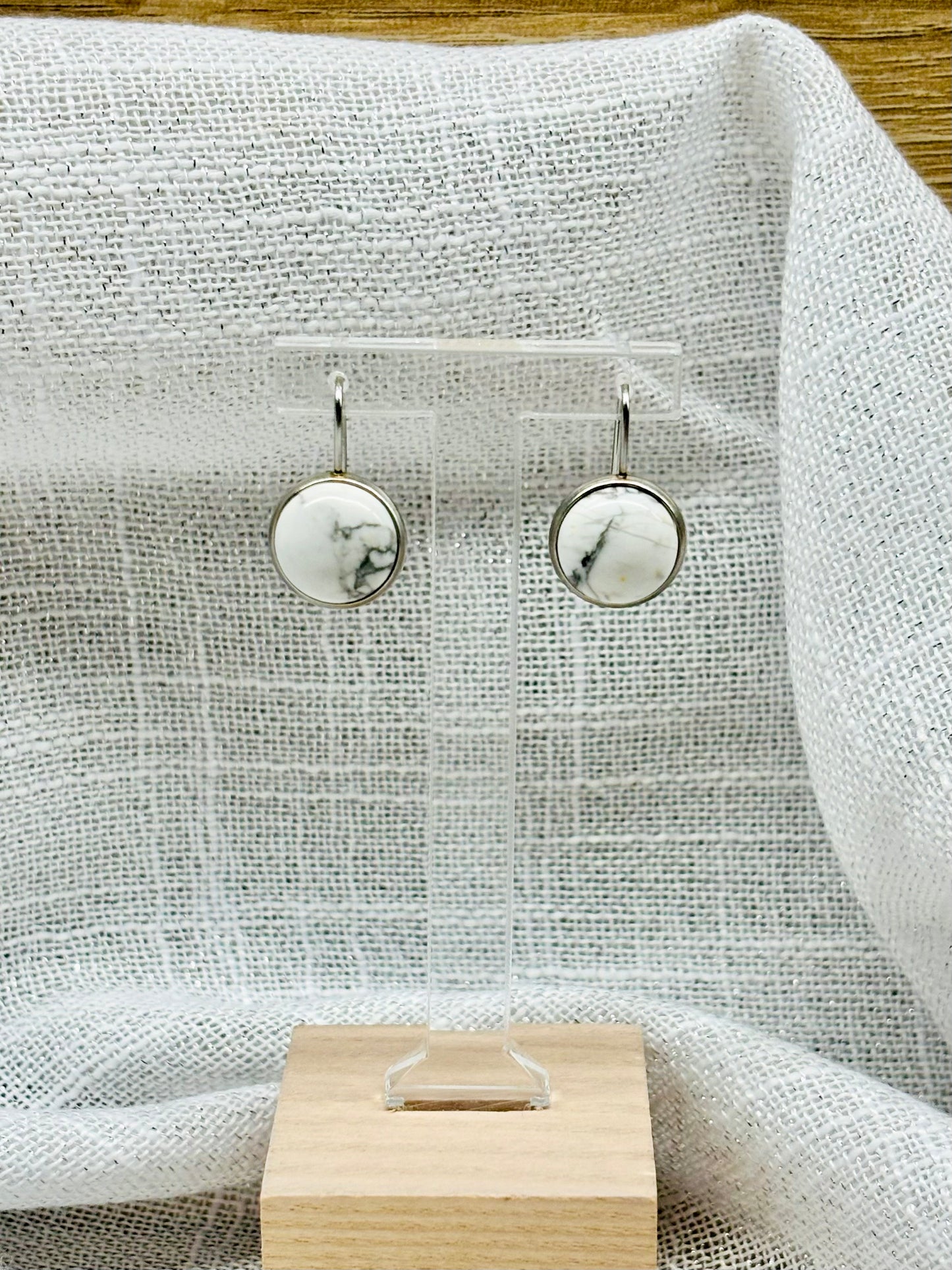 Boucles d'Oreille THÉANA, avec pierre d'howlite, exposées sur un fond en lin.