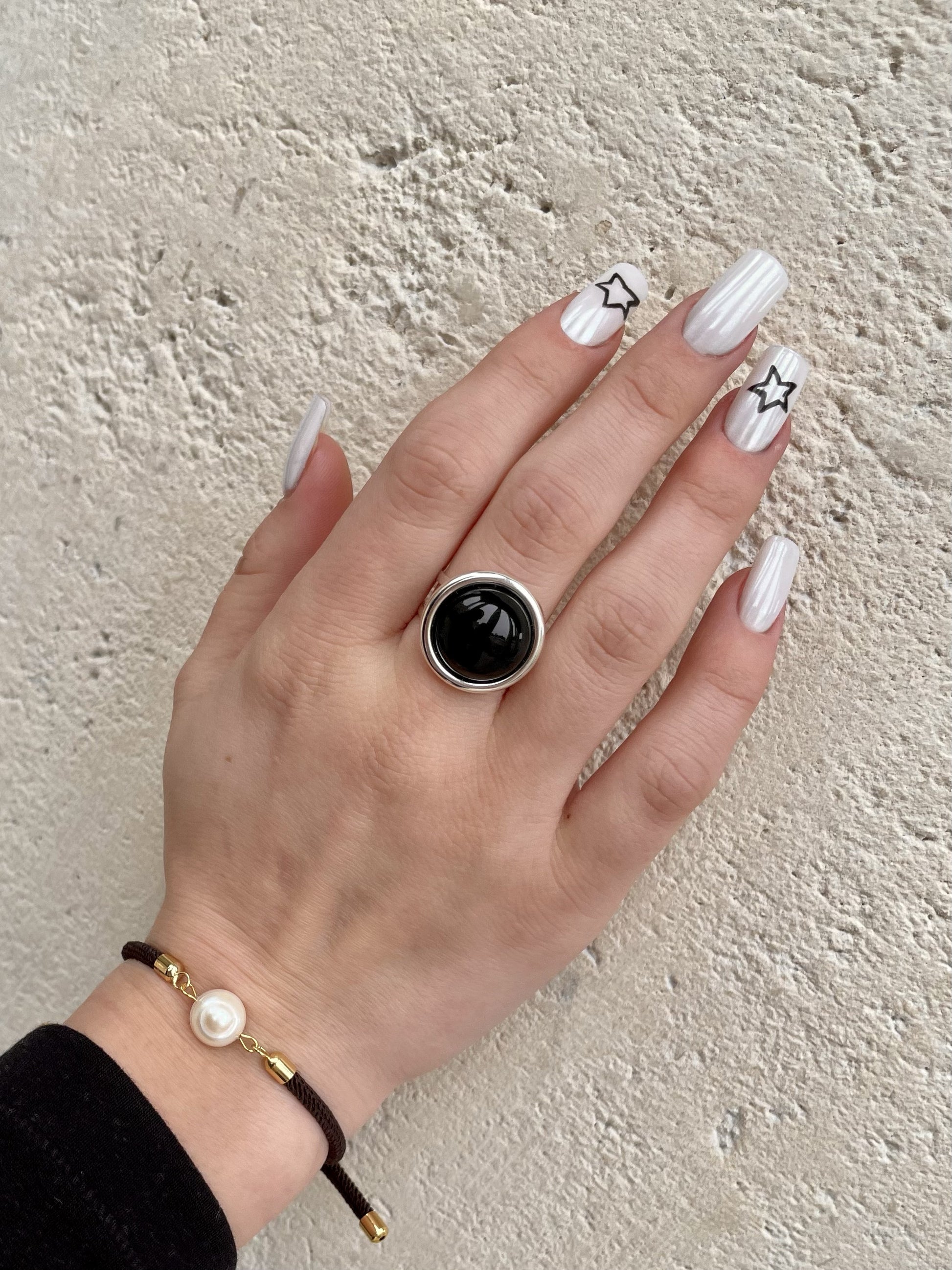 Bague THÉA, en argent et pierre d'Agate, portée sur une main de femme.