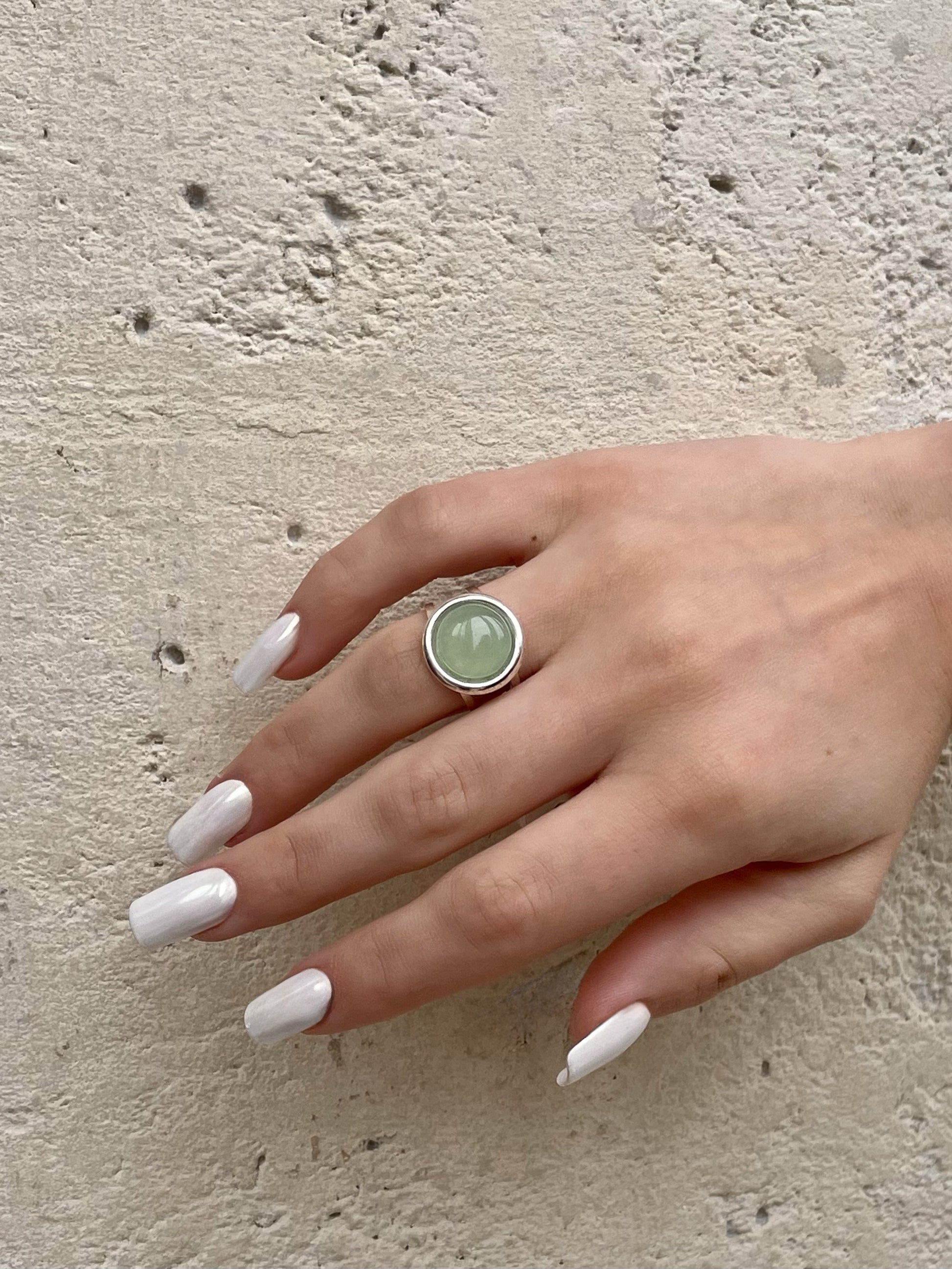 Bague THÉA, en argent et pierre d'Aventurine, portée sur une main de femme.