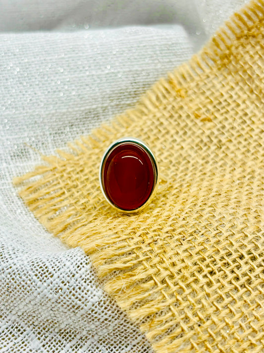 Bague THÉA, en argent et pierre de Cornaline, sur un fond de lin et toile de jute.