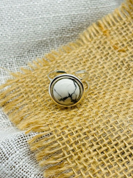 Bague THÉA, en argent et pierre d'Howlite, sur un fond en lin et toile de jute.