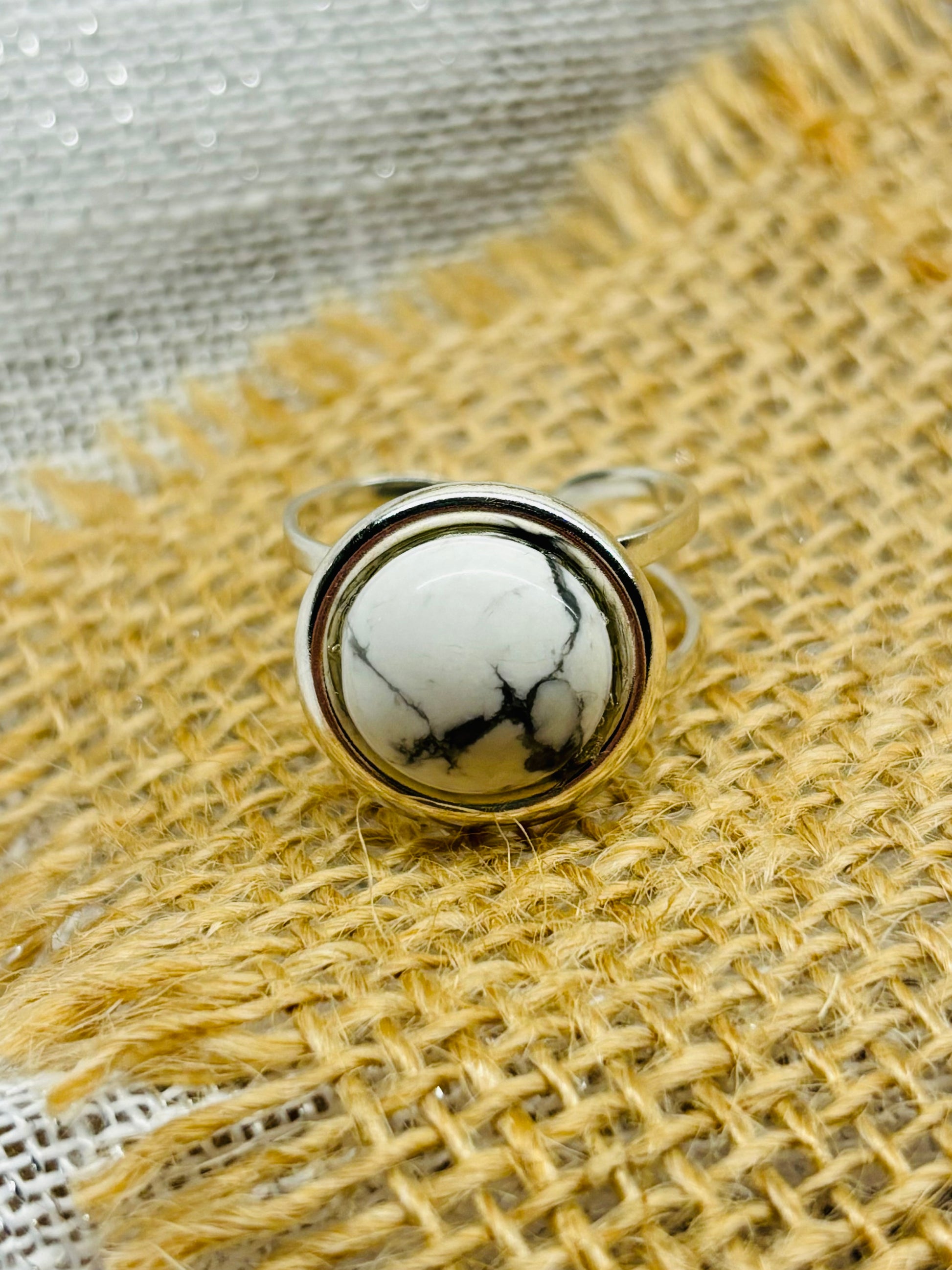 Bague THÉA, en argent et pierre d'Howlite, sur un fond en lin et toile de jute.