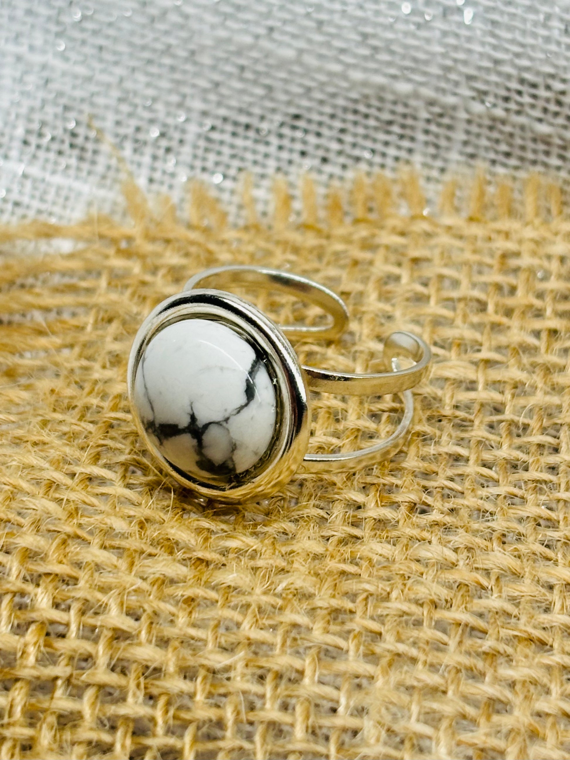Bague THÉA, en argent et pierre d'Howlite, sur un fond en lin et toile de jute.